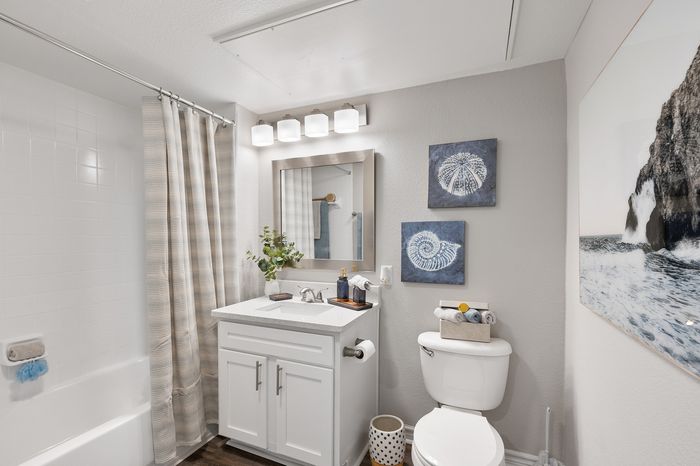 Bright and modern bathroom featuring elegant vanity with granite countertop, stylish mirror, and soothing ocean-themed decor.