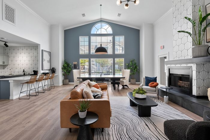 Modern open-concept living room with high ceilings, stylish decor, and abundant natural light from large arched windows.