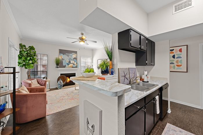 Chic open-concept living area with stylish kitchen, cozy fireplace, and inviting seating, enhanced by modern decor and natural light.