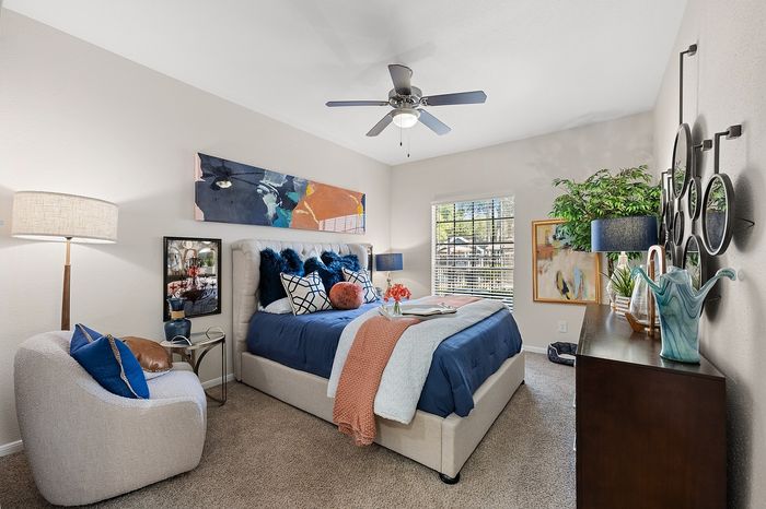 Inviting bedroom with chic decor featuring a plush bed, elegant artwork, and abundant natural light through a large window.