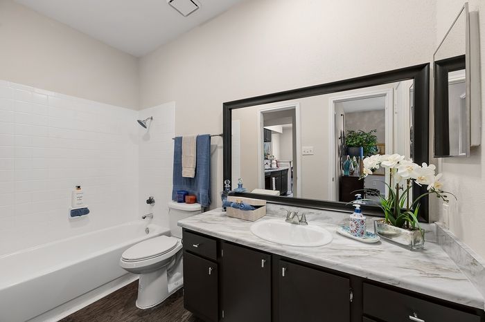Sleek modern bathroom with elegant fixtures, marble countertop, and a large mirror creating a roomy feel.