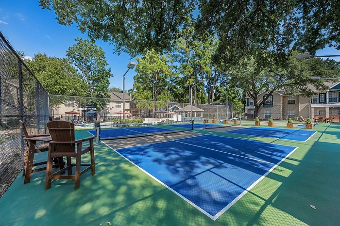 Vibrant outdoor tennis courts surrounded by lush greenery and stylish residences, perfect for active living.