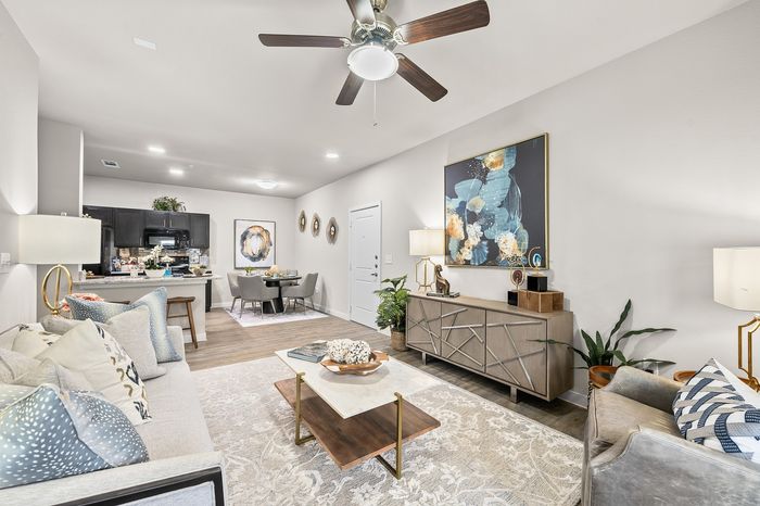 Elegant apartment living room with modern decor, featuring cozy sofas, stylish artwork, and a dining area leading to a contemporary kitchen.