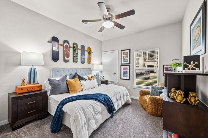 Vibrant bedroom showcasing a modern design with skateboard-themed wall decor, cozy bed dressed with colorful pillows, and stylish furniture.