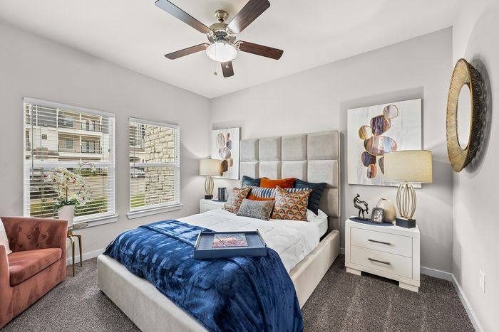 Elegant bedroom with luxurious bedding, modern decor, and ample natural light from large windows.