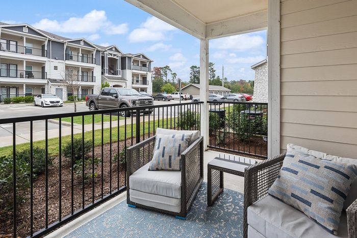 Charming apartment balcony with cozy seating, scenic views of modern architecture, and lush greenery, ideal for relaxation.