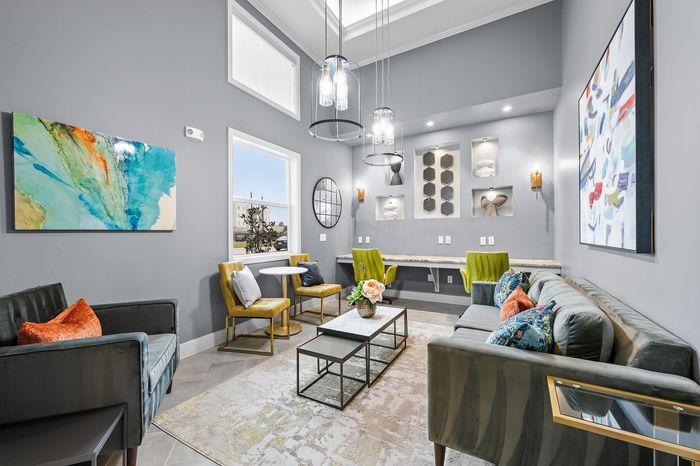 Elegant living room with modern gray walls, vibrant artwork, plush seating, and chic lighting, creating a stylish and cozy ambiance.