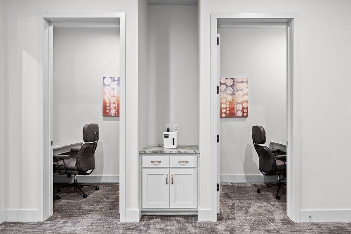 Modern dual workspace setup with sleek desks, comfortable chairs, and vibrant wall art, ideal for productivity and focus.