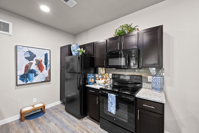 Modern kitchen with elegant dark wood cabinets, sleek black appliances, and contemporary art for a stylish touch.