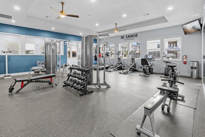 Modern gym with vibrant blue walls, featuring state-of-the-art fitness equipment including treadmills, weight racks, and a rowing machine, perfectly lit and ready for an invigorating workout.