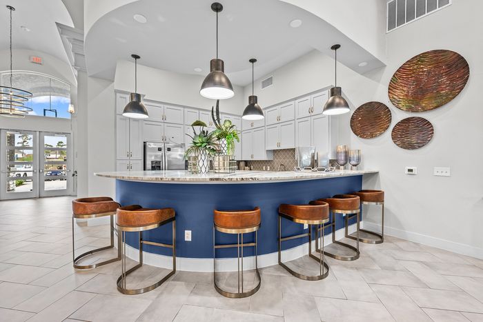 Elegant kitchen with a curved marble island, stylish pendant lighting, and modern bar stools, complemented by sleek cabinetry and artistic wall decor.