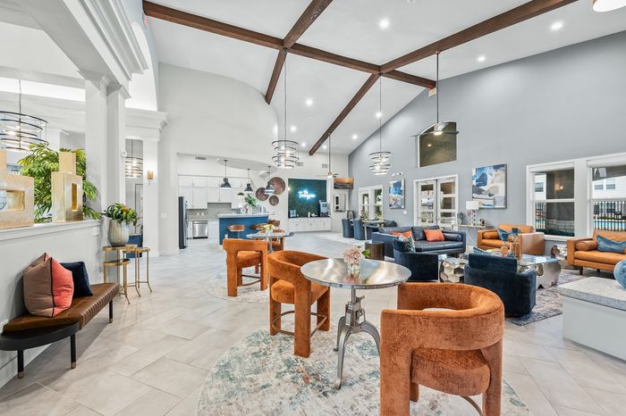 Elegant communal lounge with stylish modern seating, high ceilings showcasing wooden beams, and ambient lighting creating a welcoming atmosphere.