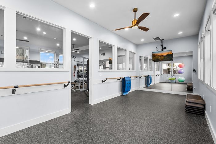 Modern fitness studio with mirrored walls, exercise equipment, and a scenic view, designed for a refreshing workout experience.