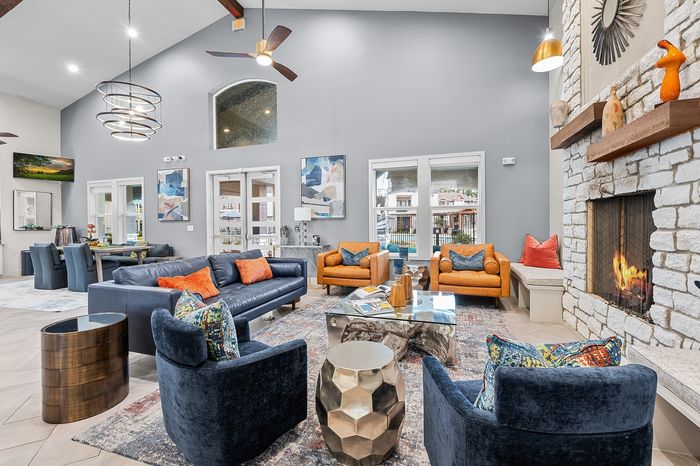 Luxurious living room with high ceilings, stylish leather furniture, modern art, and a cozy stone fireplace.