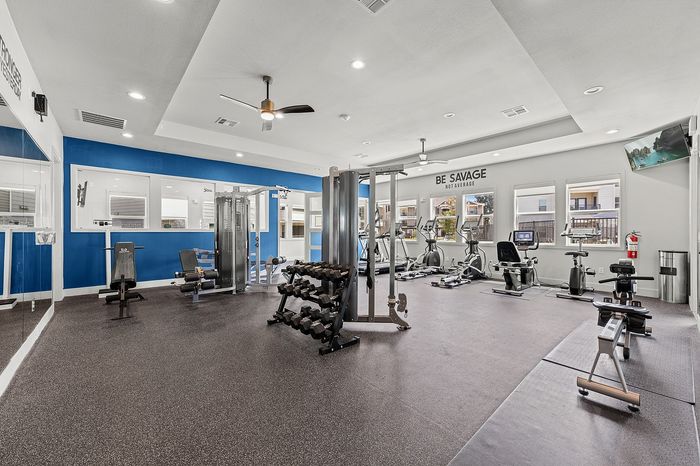 Modern fitness studio with mirrored walls, exercise equipment, and a scenic view, designed for a refreshing workout experience.