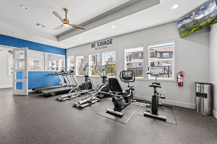 Modern fitness studio with mirrored walls, exercise equipment, and a scenic view, designed for a refreshing workout experience.