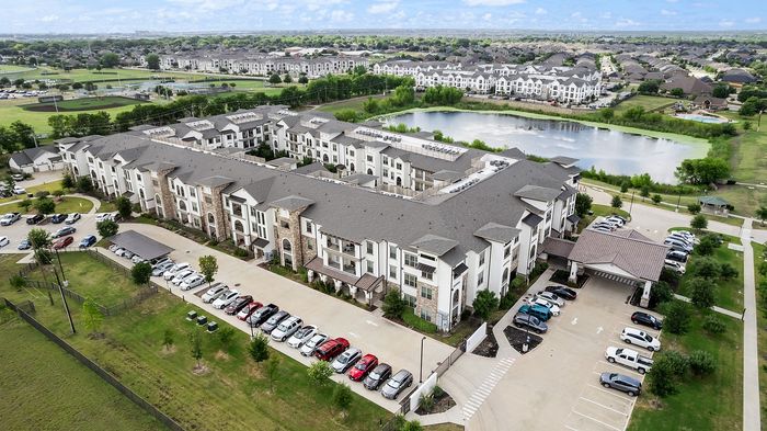 Luxurious apartment complex showcasing modern architecture, a central swimming pool, and a cozy outdoor pavilion with lush green surroundings.