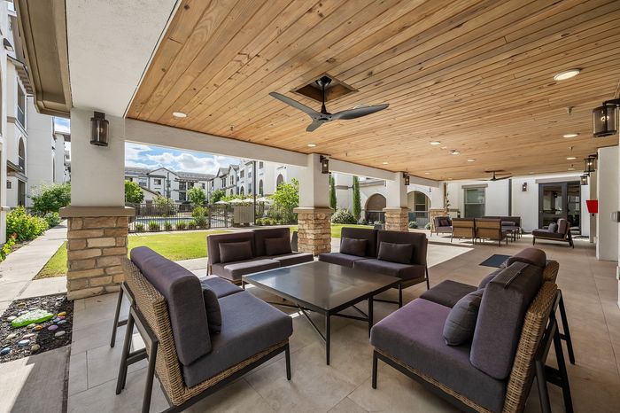 Luxurious apartment complex showcasing modern architecture, a central swimming pool, and a cozy outdoor pavilion with lush green surroundings.