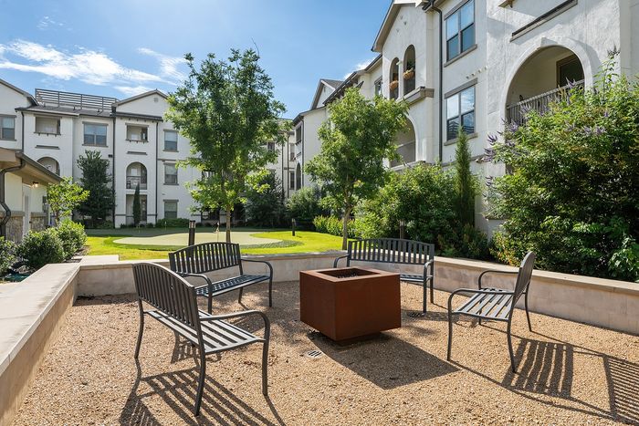 Luxurious apartment complex showcasing modern architecture, a central swimming pool, and a cozy outdoor pavilion with lush green surroundings.