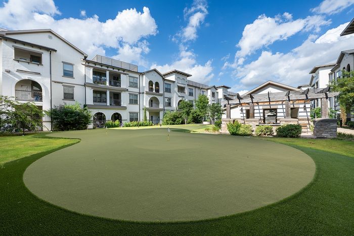 Luxurious apartment complex showcasing modern architecture, a central swimming pool, and a cozy outdoor pavilion with lush green surroundings.