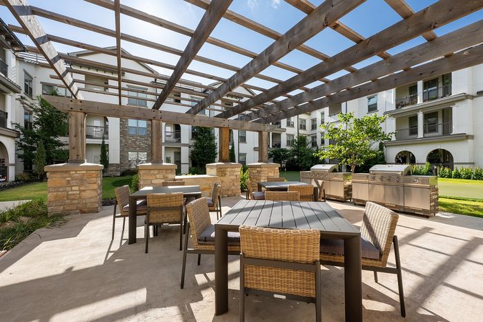 Luxurious apartment complex showcasing modern architecture, a central swimming pool, and a cozy outdoor pavilion with lush green surroundings.