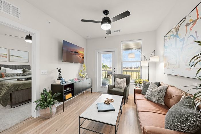 Chic apartment communal area with round tables, green seating, and panoramic nature mural, featuring a golf simulator and large windows offering serene views.