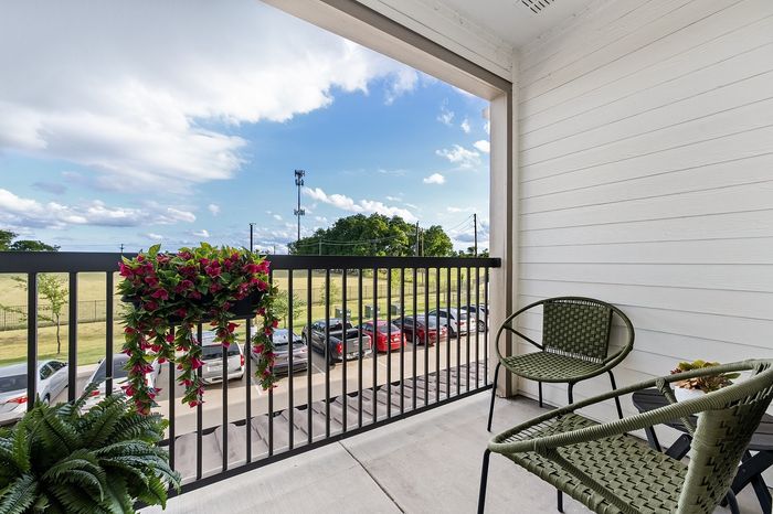 Chic apartment communal area with round tables, green seating, and panoramic nature mural, featuring a golf simulator and large windows offering serene views.