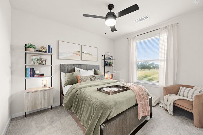Chic apartment communal area with round tables, green seating, and panoramic nature mural, featuring a golf simulator and large windows offering serene views.