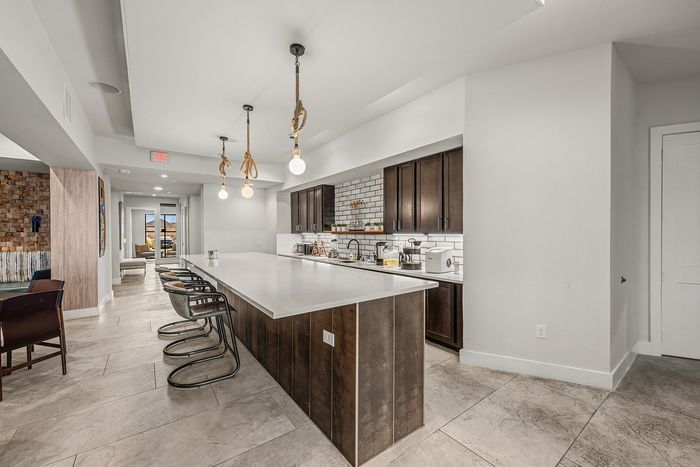 Chic recreational room with modern pool table, stylish brick walls, comfortable seating, and elegant lighting.