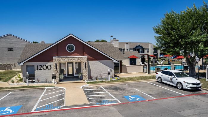 Charming community clubhouse with accessible parking, lush landscaping, and inviting outdoor pool area.