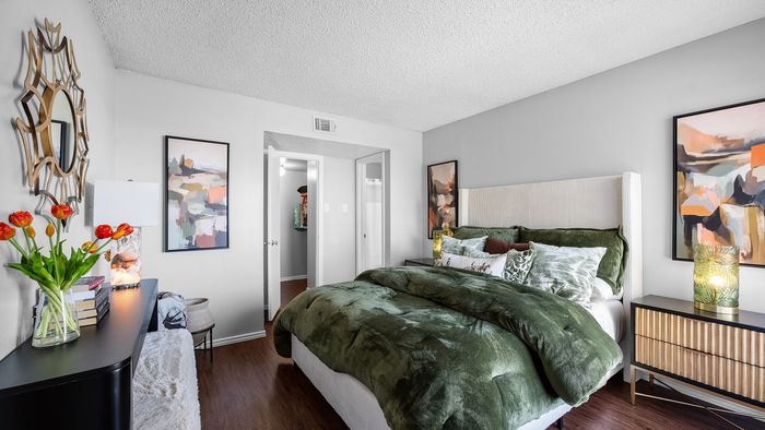 Chic bedroom featuring a plush green bedspread, modern artwork, and elegant decor enhancing the inviting ambiance.