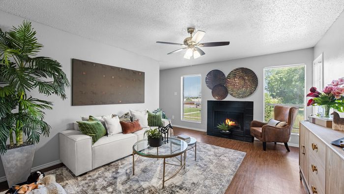 Inviting living room with cozy fireplace, chic furniture, and stylish decor under natural light.