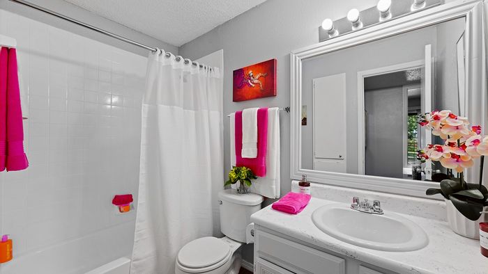 Bright and elegant bathroom with modern fixtures, featuring vibrant pink accents and fresh floral arrangements.