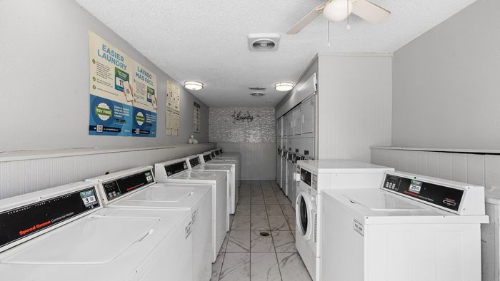 Bright and clean laundry room equipped with multiple modern washers and dryers, highlighting convenience and efficiency.