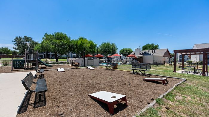 Inviting outdoor community area with a children's playground, seating benches, and a shaded picnic pergola, perfect for relaxation and social gatherings.