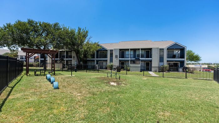 Charming apartment complex with inviting balconies, set amidst lush green lawns and mature trees, ideal for outdoor relaxation.