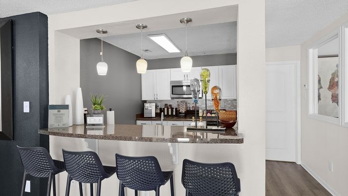 Modern kitchen with sleek white cabinets, granite countertops, and stylish pendant lighting, ideal for entertaining.