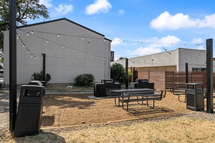 Charming outdoor space with string lights, modern BBQ grills, and picnic tables ideal for entertaining.