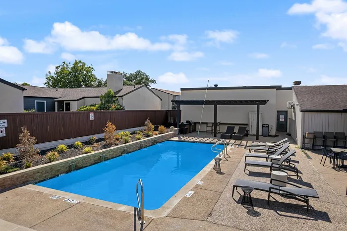 Inviting outdoor swimming pool with comfortable lounge chairs and shaded patio area, perfect for relaxation and entertaining.