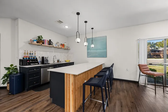Modern kitchen with sleek countertops, stylish pendant lighting, and spacious breakfast bar overlooking large windows with scenic views.