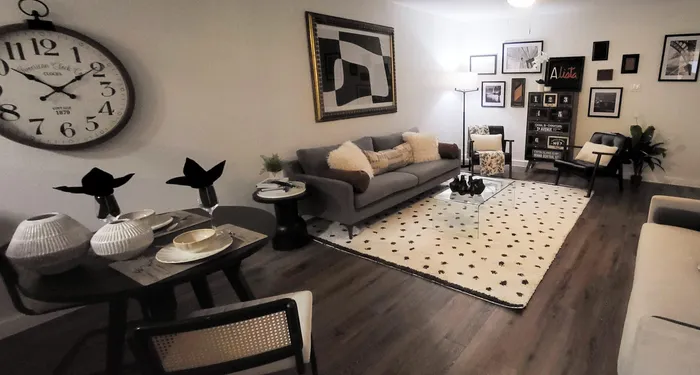 Inviting living room with chic decor, featuring a stylish gray sofa, modern wall art, and a cozy dining area with elegant table settings.