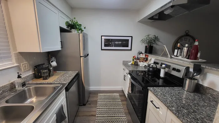 Modern kitchen with granite countertops, stainless steel appliances, and elegant white cabinetry, perfect for culinary enthusiasts.