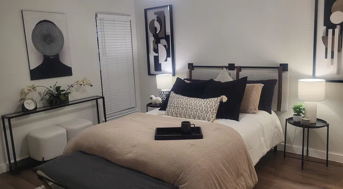 Chic bedroom with contemporary decor, featuring elegant artwork, cozy beige bedding, and stylish side tables with modern lamps.