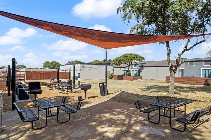 Inviting outdoor space with shaded seating areas, modern grills, and lush greenery, perfect for relaxation and entertaining.