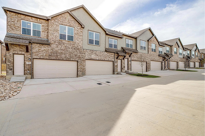 Charming townhouse community with modern brick exteriors, spacious garages, and a serene suburban setting.