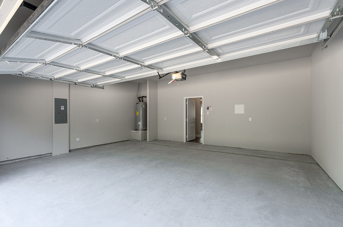 Spacious, modern garage with a sleek automatic door, ample storage space, and pristine concrete flooring.