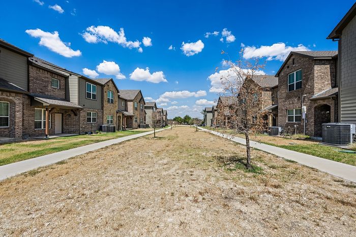 Quaint neighborhood view with charming brick townhouses under a clear blue sky, perfect for family living.
