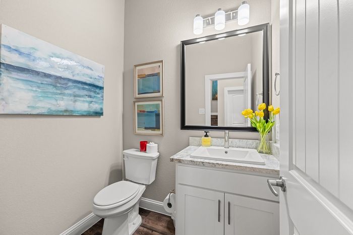 Elegant bathroom with modern fixtures, vibrant artwork, and a touch of fresh flowers beside the sink.