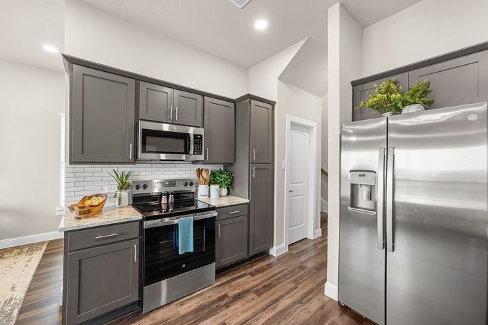 Modern kitchen with sleek stainless steel appliances, elegant dark cabinetry, and stylish decor, offering a warm and inviting atmosphere.