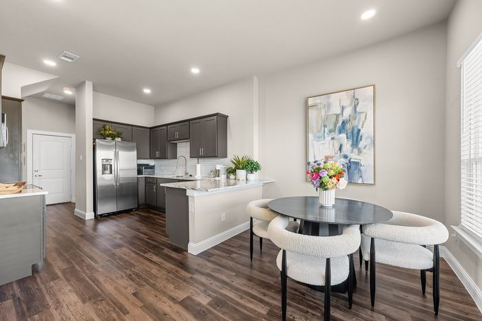 Modern kitchen with sleek cabinets, stainless steel appliances, and a cozy dining area with plush chairs and vibrant artwork.